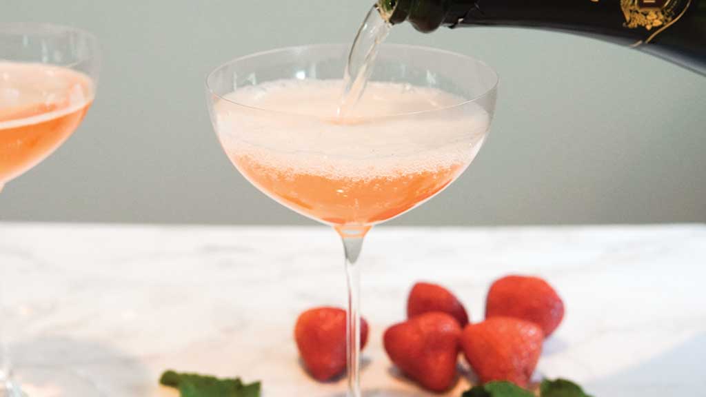 Pouring Champagne Strawberries and Mint on Table Coupe Glass