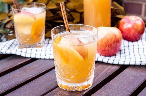 Apple Cider Old Fashioned on Wooden Table with Apples in Background