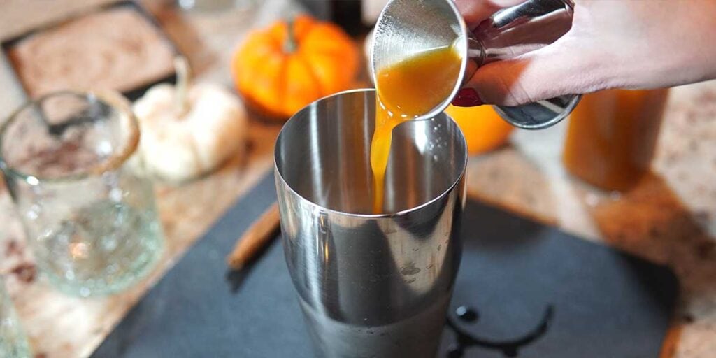 PUMPKIN SPICE SIMPLE SYRUP BEING POURED FOR PUMPKIN SPICE MARGARITAS