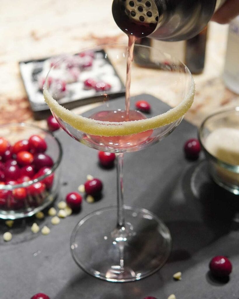 Pouring the Cranberry Bliss Cocktail in a saucer glass