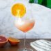 Aperol Sprtiz Mocktail in wine glass on wood table and marble background.
