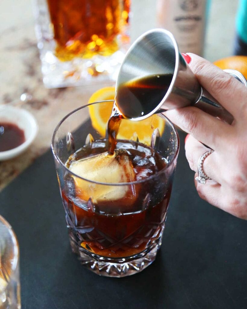 Pouring cold brew coffee into a cold fashioned cocktail