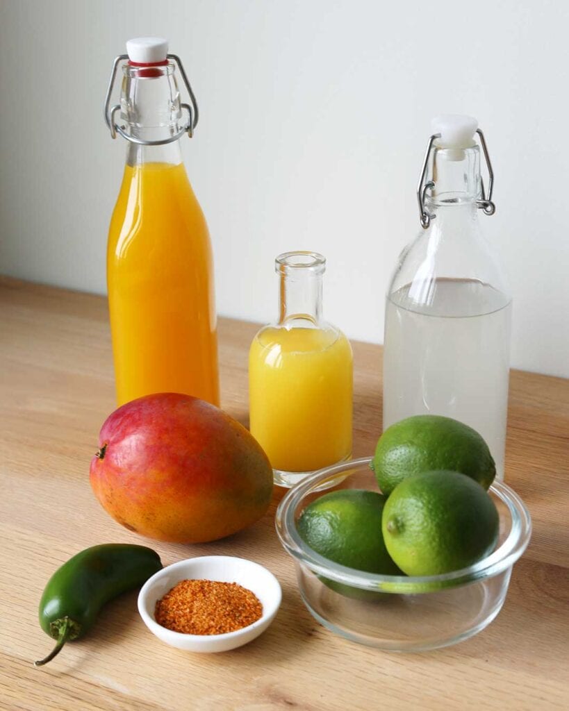 Spicy Mango Mocktail Ingredients; Mango Juice, Orange Juice, Sparkling Limeade, Mango, Lime, Jalapeno and Tajin