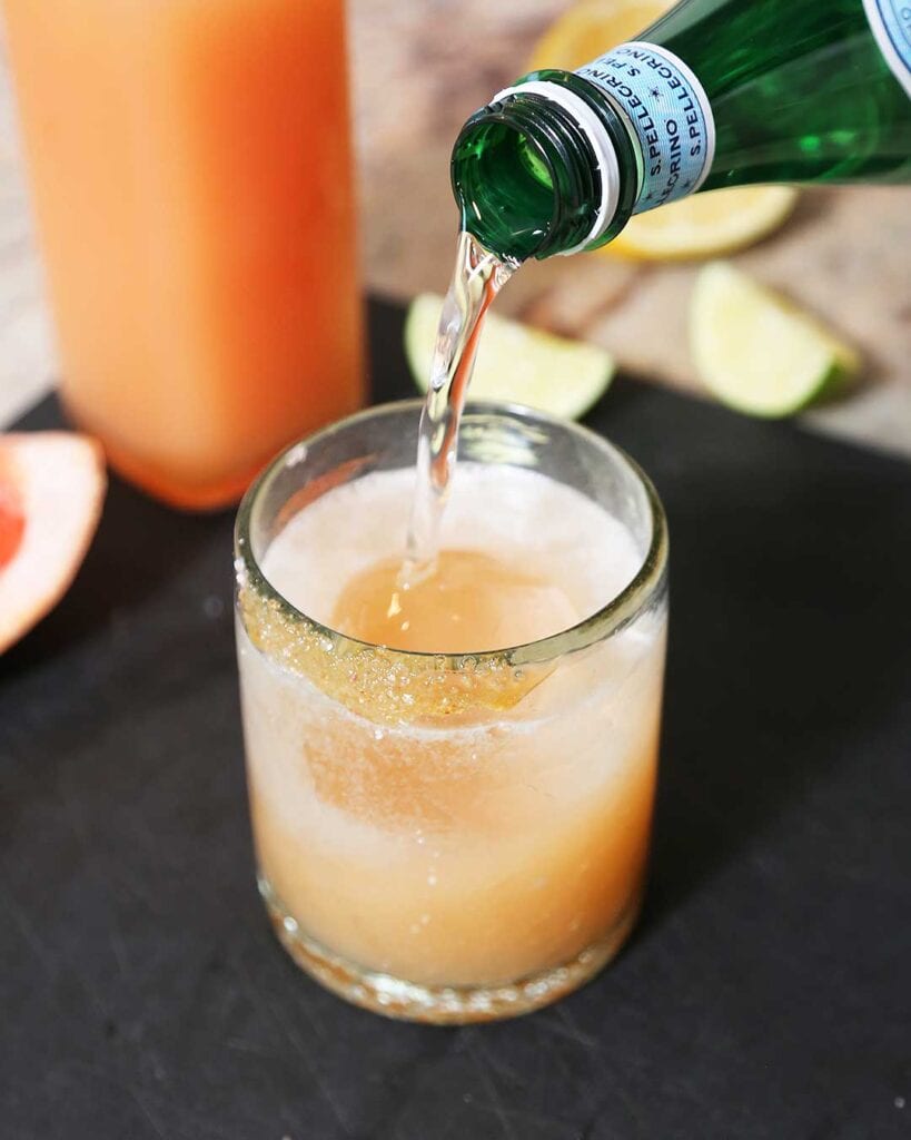 Topping paloma mocktail with sparkling water